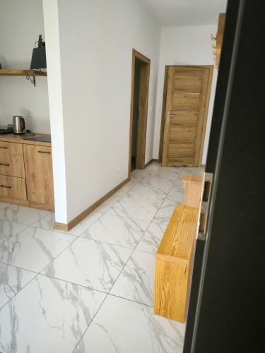 a kitchen with white marble floor and wooden cabinets at Roztoczańska Przystań in Majdan Sopocki
