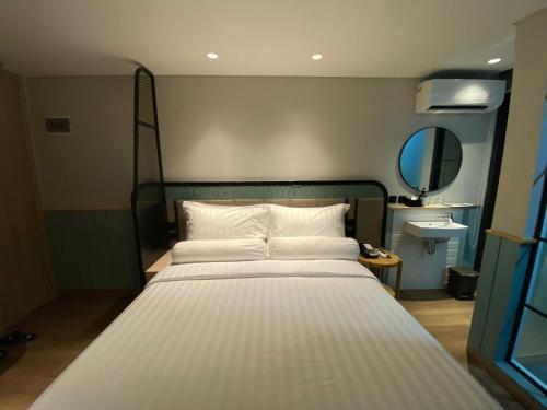 a large white bed in a room with a mirror at Luxeur Jakarta - Setiabudi in Jakarta