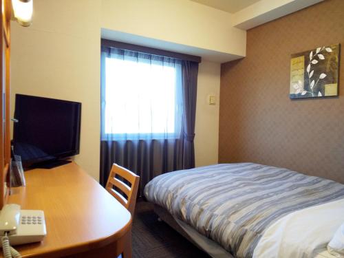 a bedroom with a bed and a desk with a computer at Hotel Route-Inn Hamamatsu Nishi Inter in Hamamatsu