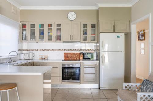 a kitchen with white cabinets and a white refrigerator at Fish Cottage Ulladulla - Linen not supplied - 3 bedroom house - sleeps 8 - pet friendly in Ulladulla