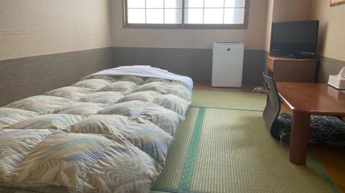 a room with two beds in a room with a table at Business Hotel Ekimae in Hakodate