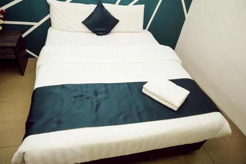 a large bed with white sheets and a blue pillow at V Hotel Titiwangsa in Kuala Lumpur