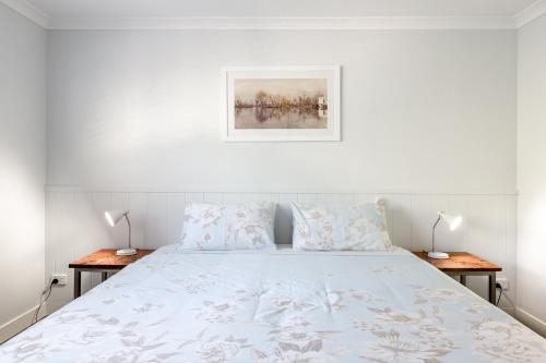 a white bedroom with a bed with two tables at Marri Lodge - 2 Bedroom with Ensuites Spacious Townhouse in Margaret River Town