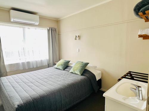 a small bedroom with a bed and a sink at Seagulls Guesthouse in Mount Maunganui