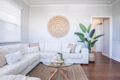 a white living room with a white couch and a table at Kings Beach Coastal Getaway, Bring the dog! in Caloundra