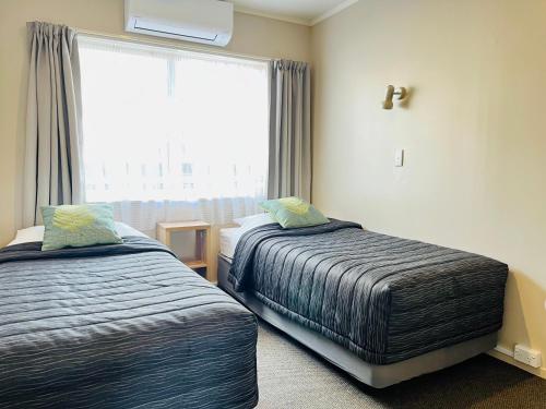 a bedroom with two beds and a large window at Seagulls Guesthouse in Mount Maunganui