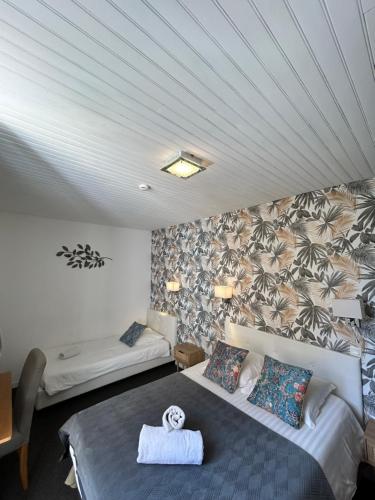 a hotel room with two beds and a wall with palm trees at Hotel du Levant in Castellane