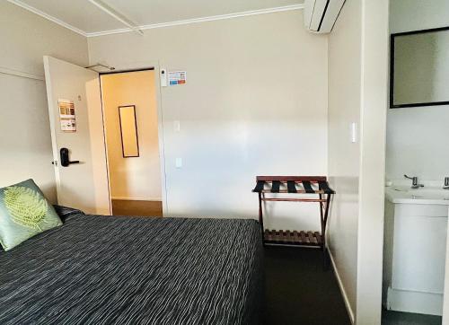 a small room with a bed and a sink at Seagulls Guesthouse in Mount Maunganui