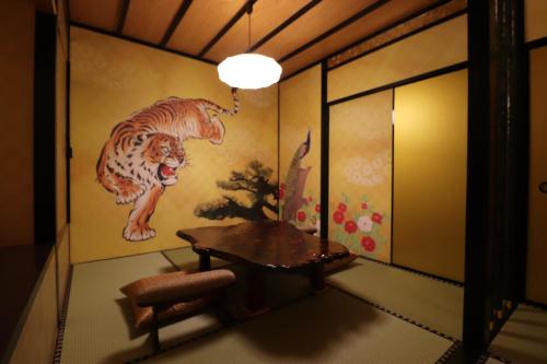 a room with a table and a painting of tigers at ホテル三愛 in Himeji