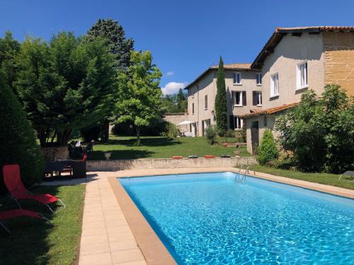a swimming pool in a yard next to a house at LES LOGES DE BACCHUS Le Carpe Diem in Chonas-lʼAmballan