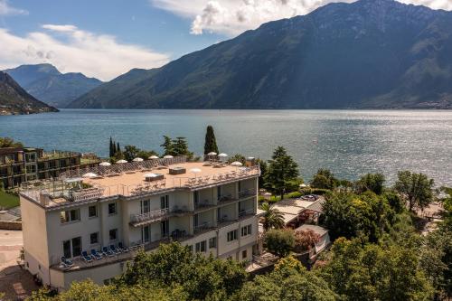 a building next to a body of water with mountains at Hotel Sogno del Benaco in Limone sul Garda