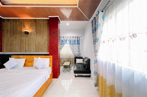 a bedroom with a bed and a chair in a room at Hotel New Dieng By Helocus in Berastagi