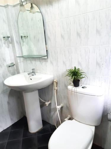 a white bathroom with a toilet and a sink at Fairland Bungalow in Kandy
