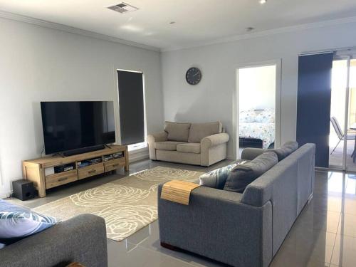 a living room with two couches and a flat screen tv at Bunker View in Port Hughes
