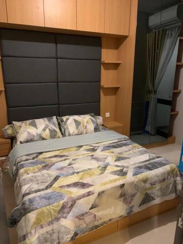 a bed with a comforter on it in a bedroom at One Residence Apartment Batam in Batam Center