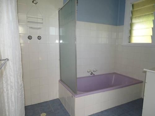 a bathroom with a purple tub and a window at Sun on the Stubble in Maitland