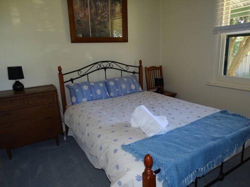 a bedroom with a bed with blue sheets and a window at Sun on the Stubble in Maitland