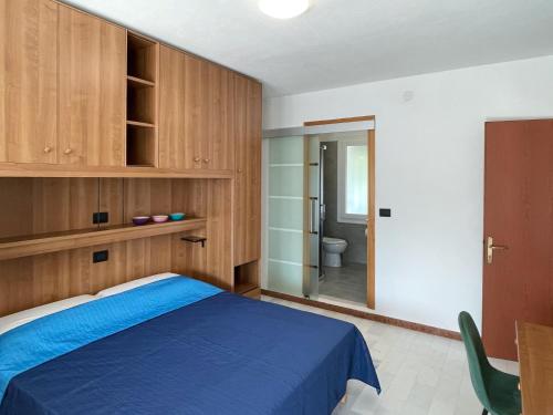 a bedroom with a blue bed and a bathroom at Smart Residence Aviano in Aviano
