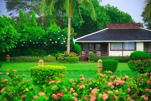 a house with a green yard with bushes and flowers at Bagan Thiripyitsaya Sanctuary Resort in Bagan