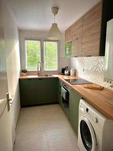 - une cuisine avec des placards verts et un lave-linge/sèche-linge dans l'établissement Charmant appart avec vue sur lac, à Savigny-le-Temple