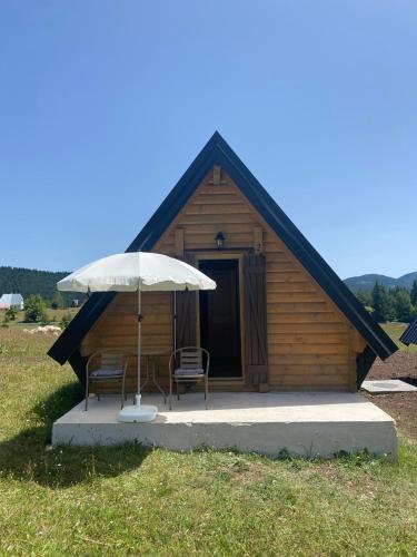 a wooden cabin with two chairs and an umbrella at Podgora 1 in Žabljak