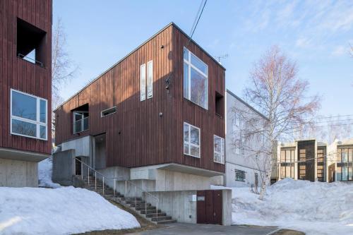 a wooden building with stairs in the snow at Forest Estate in Niseko