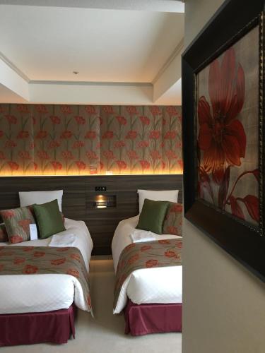 a hotel room with two beds and a painting on the wall at KKR Hotel Kumamoto in Kumamoto