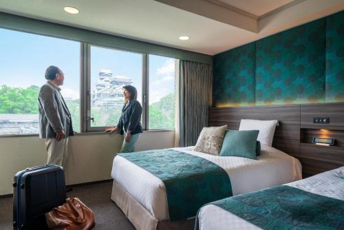 two people standing in a hotel room looking out the window at KKR Hotel Kumamoto in Kumamoto