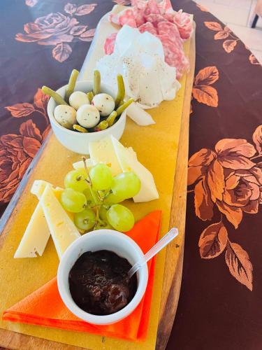 a tray with cheese and grapes and a bowl of sauce at Agri-alloggio le Poscole Al Canton in Castelgomberto