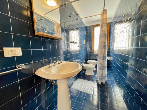 La salle de bains est pourvue de carrelage bleu, d'un lavabo et de toilettes. dans l'établissement Holiday Home Porto Santa Margherita Beach, à Porto Santa Margherita