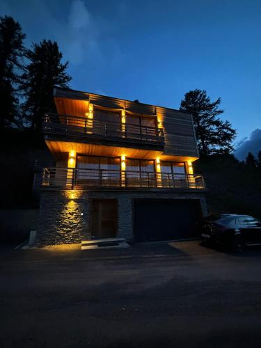 a house with lights on the side of it at night at Un Écrin de Sérénité Face aux Montagne chalet nathalya in Vars