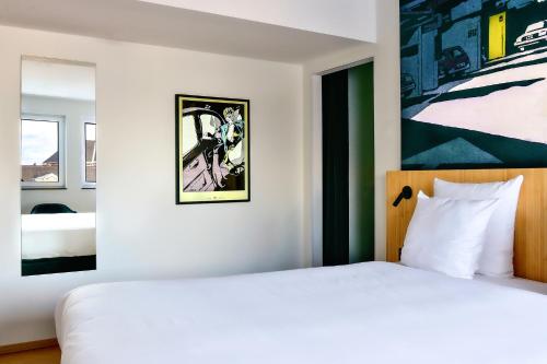 a bedroom with a white bed and a painting on the wall at Comic Art Hotel in Ghent