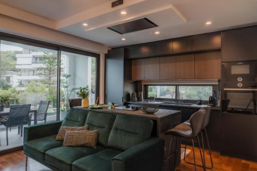 a living room with a green couch and a kitchen at Emerald Stone Apartment Varkiza in Vari