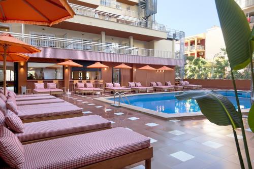 a hotel with a pool and chairs and a building at tent Bahia de Palma in El Arenal