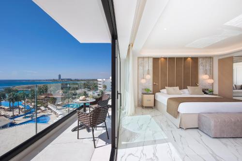 a bedroom with a bed and a balcony with a view at Adams Beach Hotel & Spa in Ayia Napa