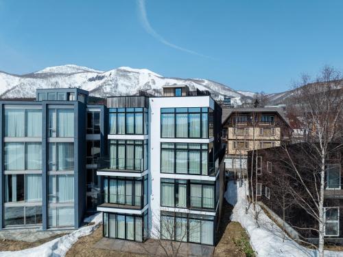 an apartment building with glass windows in front of mountains at Loft Niseko in Kutchan