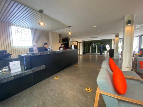 a lobby with a bar with orange pillows on a couch at Moji Don Mueang Airport Hotel - Bangkok in Bangkok