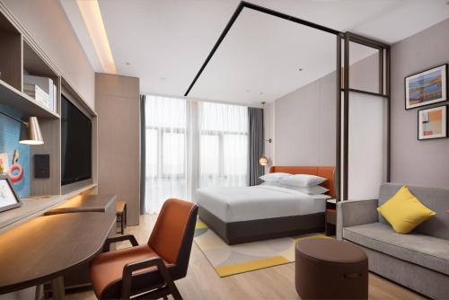 a bedroom with a bed and a desk and a couch at Home2 Suite by Hilton Changsha Ningxiang in Ningxiang