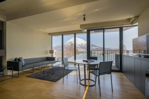 a living room with a table and chairs and a mountain at MUSE Niseko in Kutchan