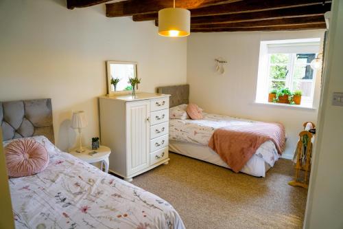 ein Schlafzimmer mit zwei Betten und einem Spiegel in der Unterkunft The Hangmans Cottage in Abbotskerswell