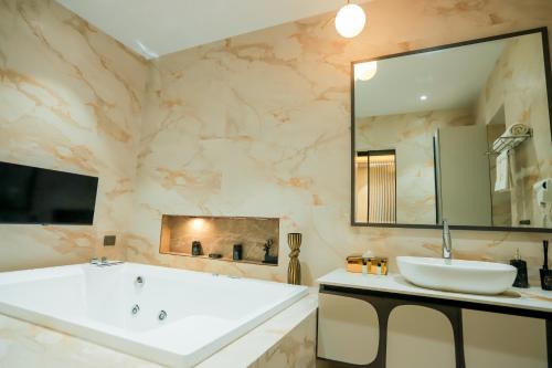 een badkamer met een groot bad en een wastafel bij Bel-La Monde Hotel Chhattarpur South Delhi in Sat Bari