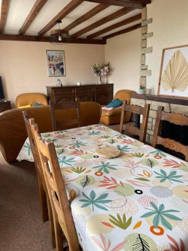 une salle à manger avec une table et un tissu de table fleuri dans l'établissement Maison proche plage, à Flamanville