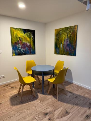 a table and chairs in a room with paintings at Tkalcovna U Zlatého potoka in Dobřany
