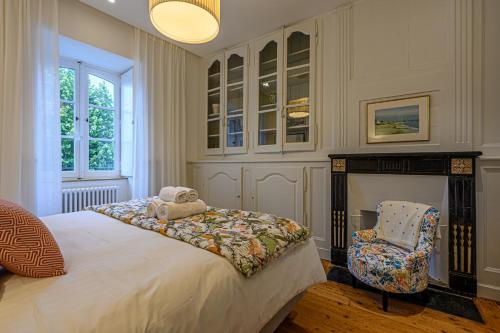 une chambre avec un grand lit et une chaise dans l'établissement La Demeure de l'Armateur - Appt vue port de Vannes, à Vannes