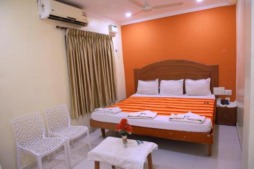 a bedroom with a bed with orange walls and chairs at Ferdin Home Stay in Kanyakumari