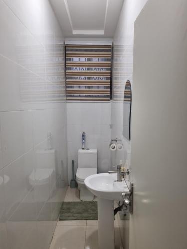 a white bathroom with a sink and a toilet at D11 New Oak in Accra