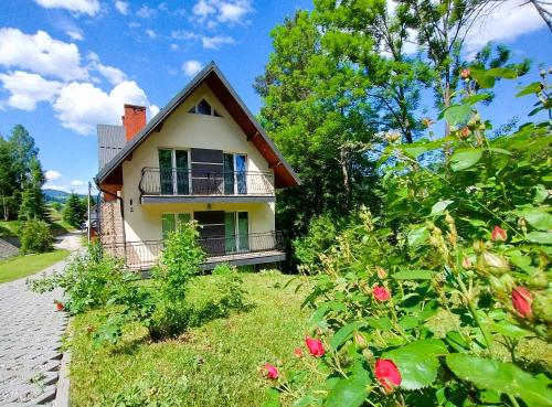 a house on a hill with flowers in front of it at Apartamenty nad potokiem in Krościenko