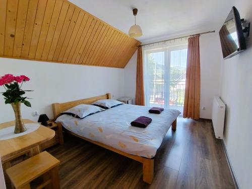 a bedroom with a bed and a large window at Apartamenty nad potokiem in Krościenko