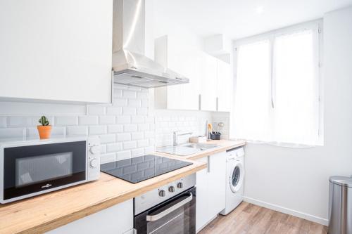 une cuisine blanche avec un évier et un micro-ondes dans l'établissement Bel Appartement F3 lumineux wi-fi, au Havre