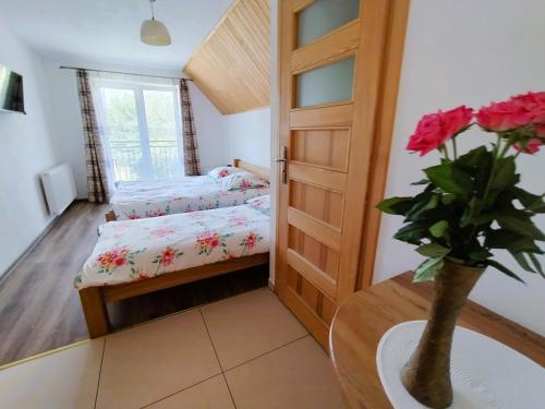 a small bedroom with two beds and a vase with roses at Apartamenty nad potokiem in Krościenko